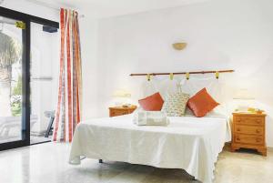 1 dormitorio con cama blanca y almohadas de color naranja en Venecia Mijas Golf Resort Costa del Sol, en Fuengirola
