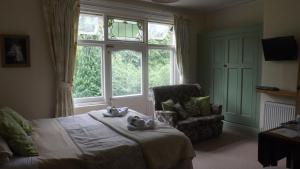 a bedroom with a bed and a chair and a window at Cedar House B&B in Matlock