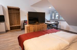 a bedroom with a bed and a flat screen tv at Pension Sewald in Berg