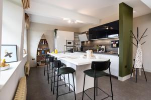 a kitchen with a white counter and bar stools at Mint Mill: New riverside apartment in historic mill in Kendal