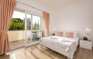 een witte slaapkamer met een bed en een groot raam bij Studio Apartment Brigita in Mlini