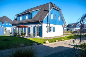 a blue and white house with a yard at Ostsee Sonnengarten in Altefähr