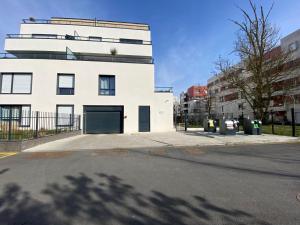 un bâtiment blanc avec garage dans une rue dans l'établissement Nouveau F2 au calme proche Paris, à Montigny-lès-Cormeilles