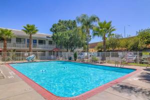 a large swimming pool with palm trees and a building at Vagabond Inn Sylmar in Sylmar