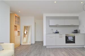 a kitchen with white cabinets and a living room at Ferienwohnung stadtnah mit Weinbergblick in Würzburg