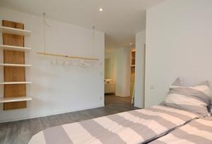 a white bedroom with a bed with a striped blanket at Ferienwohnung stadtnah mit Weinbergblick in Würzburg