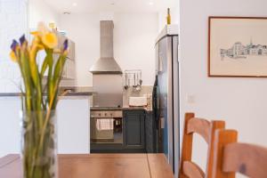 a kitchen with a refrigerator and a table with flowers at Regina's Banyuls - 2 terraces, pool and private parking in Banyuls-sur-Mer