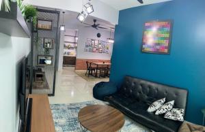 uma sala de estar com um sofá preto e uma mesa em Ammar SkyHome Ipoh em Ipoh
