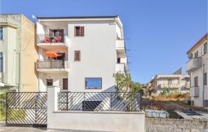 ein weißes Gebäude mit einem Balkon und einem orangenen Regenschirm in der Unterkunft 2 Bedroom Gorgeous Apartment In Trappeto in Trappeto