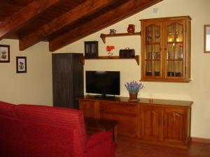 a living room with a tv and a red chair at Turismo Rural Castell in Neril