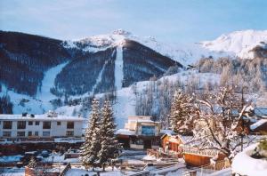 a snow covered mountain in front of a ski resort at Hôtel Las Donnas, Auron in Auron