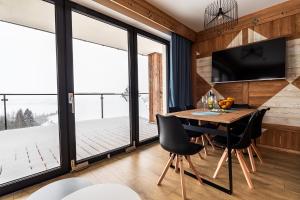 a dining room with a table and chairs and large windows at FAJNE CHATY - rodzinny wypoczynek w górach in Falsztyn