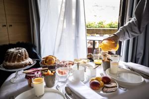 a person pouring orange juice onto a table with food at Relais et Châteaux Le Chambard in Kaysersberg