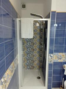 y baño con ducha de azulejos azules. en Caldi Abbracci, en Meta