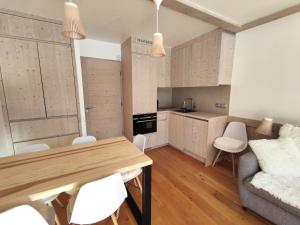 cocina y sala de estar con mesa de madera y sillas en Douglas - Appartement au cœur du Jardin Alpin, en Courchevel