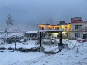 una casa con nieve en el suelo delante de ella en Breathe Inn en Kasol