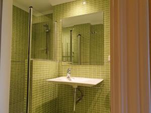ein grün gefliestes Bad mit einem Waschbecken und einer Dusche in der Unterkunft Las Mimosas, La Cala de Mijas in La Cala de Mijas