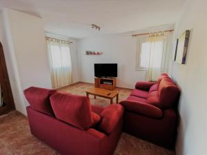 sala de estar con 2 sofás rojos y TV en Cala Mesquida en Cala Mesquida