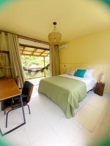 um quarto com uma cama, uma secretária e uma janela em Suítes Manjuba Praia de Sta Tereza em Ilhabela