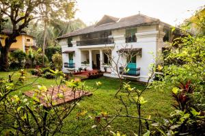 a white house with a yard in front of it at Island House Goa in Divar