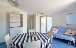 a dining room with a table and a blue couch at Stunning Apartment In Punta Braccetto Rg With Kitchen in Punta Braccetto