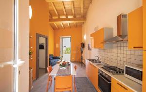 una cucina con armadi arancioni e un tavolo con sedie arancioni di Amazing Apartment In Patti With 2 Bedrooms, Wifi And Outdoor Swimming Pool a Patti