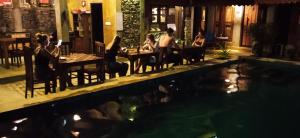 a group of people sitting at tables by a swimming pool at Negombo The Nature Villa and Cabanas in Negombo