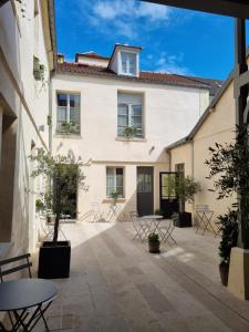 cortile di un edificio con tavoli e sedie di Hôtel Le Chantilly a Chantilly