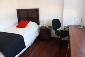 1 dormitorio con cama, escritorio y silla en Hostal Buró, en Concepción