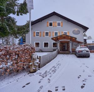 une maison avec des empreintes de pieds dans la neige devant elle dans l'établissement Landhotel Krone, à Oberreute