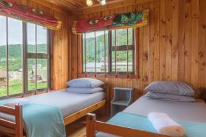 two beds in a wooden room with windows at Strandhuis in Eersterivierstrand