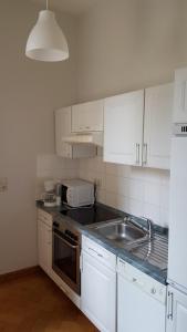 a kitchen with white cabinets and a sink and a microwave at Königliche Villa Appartement mit Balkon in Berchtesgaden