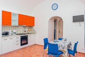cocina con mesa, sillas y reloj en Casa Cinque, en Praiano