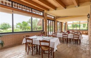 una sala da pranzo con tavoli, sedie e ampie finestre di 11 Bedroom Pet Friendly Home In Tolentino a Tolentino