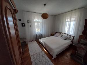 a bedroom with a bed with white sheets and windows at Casa de Vacanta Nora in Oveselu