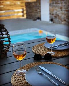 twee glazen wijn op een tafel naast een zwembad bij PARIAN WHITE LUXURY APARTMENTS in Parikia