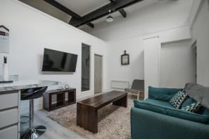 a living room with a blue couch and a tv at Hullidays-Theatre Hideout Apartment in Hull