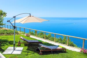 un patio con sillas, una sombrilla y el océano en Casa Cinque, en Praiano
