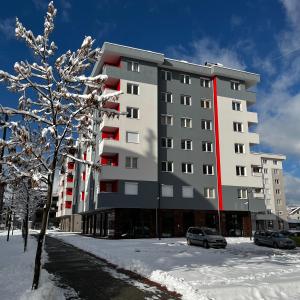 a building in the snow with cars parked in front at Ema Residence Pale Jahorina in Pale
