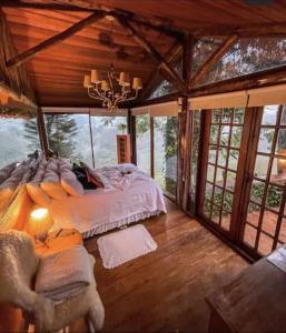 um quarto com uma cama num quarto com janelas em Chalé Vista Privilegiada em Campos do Jordão