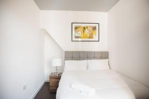 Un dormitorio con una cama blanca y una foto en la pared en Riverside park house, en Leicester