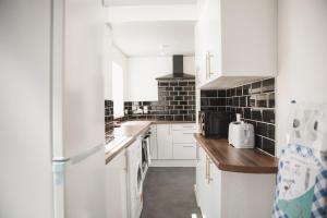 una cocina con electrodomésticos blancos y azulejos negros en Riverside park house en Leicester