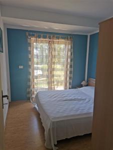 a blue bedroom with a bed and a window at Apartmani Tia in Drenje