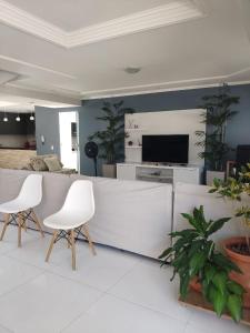 sala de estar con sillas blancas y TV en Casa Porto Di Nassau en Porto Seguro