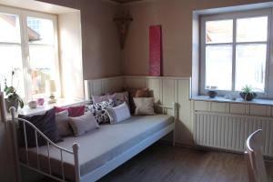 Bett mit Kissen in einem Zimmer mit Fenstern in der Unterkunft FeWo Alte Post in Oberdigisheim
