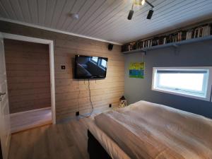 a bedroom with a bed and a tv on the wall at Lofoten, Markveien Villa in Kabelvåg