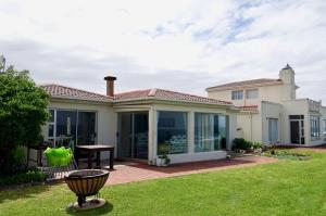 a house with a patio with a table and a grill at Whales & Waves in Hermanus