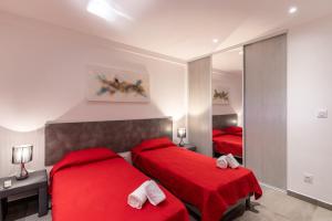 1 dormitorio con 2 camas rojas y espejo en Les Arcades de Cala Rossa, en Lecci