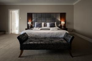 a bedroom with a large bed with a black leather couch at Buchanan Arms Hotel & Leisure Club in Drymen