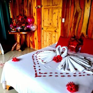 a bed with white sheets and red flowers on it at The Sunset Tucano Lodge in Drake